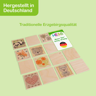 Holz-Memo-Spiel mit mehreren quadratischen Spielplättchen, die bunte Illustrationen wie Tiere und Blumen zeigen. Oben links im Bild steht „Hergestellt in Deutschland“, darunter „Traditionelle Erzgebirgsqualität“. Auf einem der Plättchen befindet sich ein Etikett mit der Aufschrift „HESS Memo 'Bär' farbig, 18-teilig 10m+ MADE IN GERMANY“.