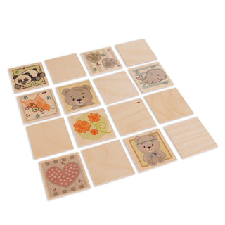 Holzspiel mit 16 quadratischen Plättchen in einer 4×4-Anordnung. Acht Plättchen zeigen bunte Illustrationen: ein Panda, Pfotenabdrücke, ein Wal, ein orangefarbener Fuchs mit Schmetterling, eine orange Blume mit grünen Schnörkeln, zwei verschiedene Bären (einer mit Fliege, einer mit Herz) und ein rosa Herz mit Punkten. Die übrigen acht Plättchen sind leer.