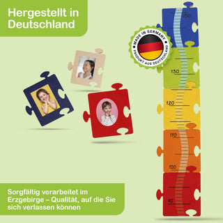 Bunte Messlatte aus Puzzleteilen mit Höhenangaben von 70 cm bis 150 cm, farblich abgestuft von Rot (unten) bis Blau (oben). Um die Messlatte sind vier zusätzliche Puzzleteile mit Fotos von Kindern angeordnet. Oben links steht „Hergestellt in Deutschland“, unten links „Sorgfältig verarbeitet im Erzgebirge – Qualität, auf die Sie sich verlassen können“. Ein rundes Siegel mit deutscher Flagge und dem Text „Made in Germany – Produkt aus Deutschland“ befindet sich mittig rechts.