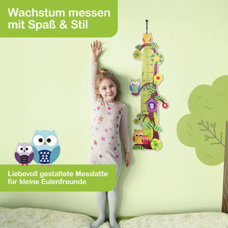 Ein Kind steht neben einer farbenfrohen Messlatte und streckt den rechten Arm nach oben, um seine Größe zu messen. Die Messlatte ist mit Eulenmotiven und Blumen dekoriert. Oben links steht der Schriftzug ‚Wachstum messen mit Spaß & Stil‘. Unten links sind zwei gezeichnete Eulen mit dem Text ‚Liebevoll gestaltete Messlatte für kleine Eulenfreunde‘.