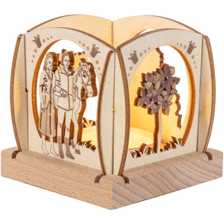 Der kleine Teelichthalter aus naturbelassenen Holz ist quadratisch und mit abgerundeten Enden und verschiedenen Blenden versehen. Zu sehen ist das Zauberbäumchen und das Prinzenpaar mit Pferd. Dieses Bild zeigt den beleuchteten Teelichthalter. Bild 4.