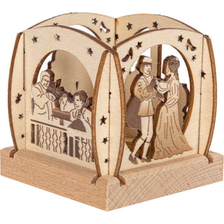 Der kleine Teelichthalter aus naturbelassenen Holz ist quadratisch und mit abgerundeten Enden und verschiedenen Blenden versehen. Dargestellt wird das Märchen vom Aschenbrödel. An zwei von vier Seiten wird das tanzende Prinzenpaar und die musizierende Schlosskapelle gezeigt. Mit einem Teelicht könnte man das Märchen gemütlich erhellen. Bild 3.