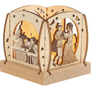 Der kleine Teelichthalter aus naturbelassenen Holz ist quadratisch und mit abgerundeten Enden und verschiedenen Blenden versehen. Dargestellt wird das Märchen vom Aschenbrödel. An zwei von vier Seiten wird das tanzende Prinzenpaar und die musizierende Schlosskapelle gezeigt. Mit einem Teelicht wird das Märchen gemütlich dargestellt. Bild 1.