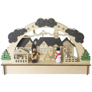 LED-Holz-Lichterbogen mit einem liebevoll gestalteten Dorfmotiv: Mehrere Häuser mit detaillierten Fenstern und Dächern sowie eine Kirche mit Turm stehen im Zentrum. Links und rechts rahmen zwei Bäume die Szene ein. Im Vordergrund befinden sich eine Holzfigur in Winterkleidung und ein Schneemann mit rotem Schal und schwarzem Hut. Ein Bogen mit Sternen und Wolken überspannt das gesamte Arrangement.