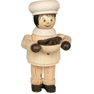 Die Abbildung zeigt eine Holzfigur eines Bäckermädchens. Die Figur hält eine Schüssel mit kleinen Gebäckstücken. Die Bäckerin trägt eine weiße Mütze, einen weißen Schal und ein naturfarbenes Hemd, dazu braune Hosen und schwarze Schuhe.