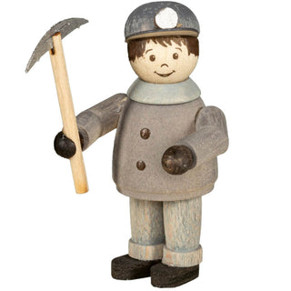 Die Abbildung zeigt eine Holzfigur eines Bergmanns. Die Figur trägt eine graue Kleidung mit schwarzen Handschuhen und Stiefeln sowie einen grauen Helm mit einer Grubenlampe vorne. Der Bergmann hält in der rechten Hand eine Schaufel. Die Gesichtszüge sind einfach aufgemalt, einschließlich Augen, Augenbrauen und einem lächelnden Mund.