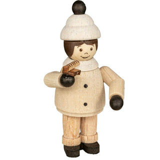 Die Abbildung zeigt eine Holzfigur einer Person, die eine weiße Mütze mit einem schwarzen Bommel, einen weißen Schal und einen beigen Mantel trägt. Die Figur hat schwarze Handschuhe und schwarze Schuhe. Die Miniatur hält in der rechten Hand eine Bratwurst.