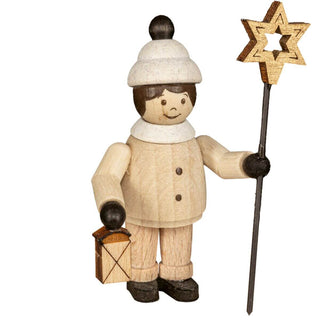 Die Abbildung zeigt eine Holzfigur einer Person, die einen weißen Hut mit einem schwarzen Bommel trägt und in der linken Hand eine Laterne sowie in der rechten Hand einen sternförmigen Stab hält. Die Figur hat einfache Gesichtszüge, darunter zwei Augen und ein Lächeln, und ist in heller Kleidung mit Knöpfen vorne gekleidet. Die Figur steht auf schwarzen Schuhen.