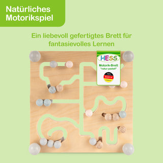 Motorikspielbrett aus Holz mit verschlungenen Bahnen und Kugeln in sanften Pastellfarben. Oben links steht der Text ‚Natürliches Motorikspiel‘ und darunter ‚Ein liebevoll gefertigtes Brett für fantasievolles Lernen‘. Auf dem Brett befindet sich ein Etikett mit der Aufschrift ‚HESS Motorik-Brett ‚natur-pastell‘‘ sowie ein Siegel ‚100% Made in Germany‘.