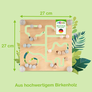 Quadratisches Motorik-Brett aus hochwertigem Birkenholz der Marke HESS, Größe 27 × 27 cm. Auf dem Brett befinden sich bunte Kugeln, die durch labyrinthartige Bahnen bewegt werden können. Im Hintergrund sind grüne Blätter sichtbar. Oben rechts auf dem Brett ist ein Etikett mit der Aufschrift ‚HESS Motorik-Brett ‚natur-pastell‘ Made in Germany‘. Unten im Bild steht der Text ‚Aus hochwertigem Birkenholz‘.
