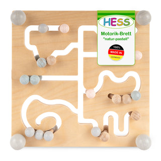 Quadratisches Motorikbrett aus Holz mit verschlungenen Pfaden, auf denen pastellfarbene Holzkugeln bewegt werden können. Oben rechts ist ein grünes Schild mit der Aufschrift ‚HESS Motorik-Brett ‚natur-pastell‘ 100% MADE IN GERMANY‘.