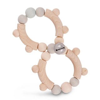 Holzspielzeug in Form einer Acht mit gebogenen Holzteilen und Holzperlen in natürlichen Farbtönen wie Beige und Hellgrau. In der Mitte des Spielzeugs befindet sich eine kleine silberne Glocke.