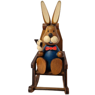 Der Osterhase in blau mit roter Fliege sitzt gemütlich im Schaukelstuhl und hält einen Vogel in der Hand_2