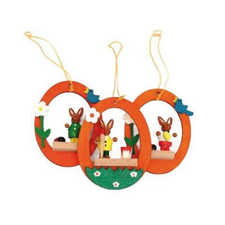 Orangefarbene Ostereier aus Holz, zum Hängen, mit farbigen Osterhasen in der Mitte