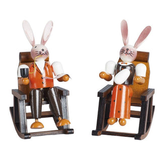 Farbiges Osterhasenpaar im Schaukelstuhl. Der Hase liest gemütlich Zeitung und raucht eine Pfeife und die Häsin hält ein Osterei in der Hand_1