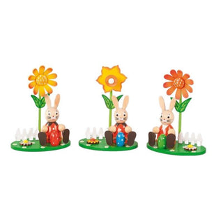 3 kleine, sitzende Osterhasen auf jeweils einem frühlinghaft, gestalteten Sockel mit Gartenzaun, Ostereiern und einer farbigen Frühlingsblume