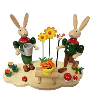 Farbiges Osterhasenpaar auf naturfarbenen Sockel im frühlingshaften Design mit vielen bunten Blumen