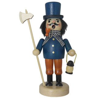 Ein Räuchermann "Nachtwächter" steht auf einem runden Sockel. Er trägt einen blauen Mantel mit goldenen Knöpfen, einen blaue Zylinder, braune Hose und schwarze Stiefel. Der bärtige Mann hat ein Pfeifchen im Mund, hält eine Axt in der einen Hand und eine kleine Laterne in der anderen.