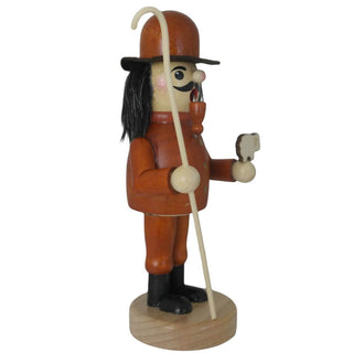 Ein hölzerner Räuchermann in der Rolle eines Schäfers steht auf einem runden Sockel. Er trägt einen orangefarbenen Mantel mit zwei Knöpfen, schwarze Stiefel und einen braunen Hut. Der bärtige Mann hält ein kleines weißes Schaf in der linken Hand und einen langen Hirtenstab in der rechten. Seitenansicht