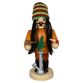Das Bild zeigt ein Räuchermännchen namens „Cannabis-Freund – Karl der Kiffer“, das 20 cm groß ist. Es trägt eine bunte Mütze in den Farben Rot, Gelb und Grün sowie schwarze Zöpfe. Das Räuchermännchen hat einen orangefarbenen Mantel mit einem grünen Hanfblatt auf der Vorderseite. In der linken Hand hält es einn Joint, in der rechten Hand eine Art getrocknetes Pflanzenmaterial. Vor dem Räuchermännchen steht ein silberne Wasserpfeife.