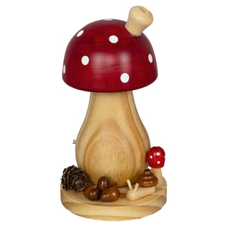 Holzfigur eines Fliegenpilzes zum Abbrennen von Räucherkerzen mit rotem Hut und weißen Punkten, auf einem runden Holzsockel stehend, umgeben von kleinen Holzdekorationen wie Eicheln, einem Tannenzapfen und einer kleinen Pilzfigur.