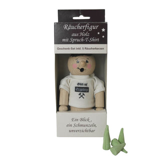 Eine hölzerne Räucherfigur mit einem weißen T-Shirt, auf dem "Glück auf Erzgebirge" und zwei gekreuzte Hämmer abgebildet sind. Die Figur hat ein freundlich bemaltes Gesicht und trägt eine schwarze Mütze. Inklusive 5 Räucherkerzen.
