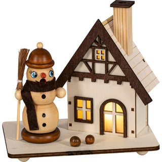 Räuchermännchen in Form eines Schneemanns mit naturfarbenem Finish, neben einem beleuchteten Fachwerkhaus, batteriebetrieben, Höhe 16 cm