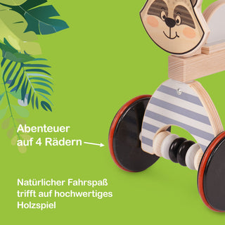 Ein hölzernes Spielzeugfahrzeug mit vier Rädern und einem Waschbärkopf an der Vorderseite. Das Fahrzeug ist in hellen Farben gestaltet. Im Hintergrund sind grüne Blätter zu sehen. Auf dem Bild steht der Text: „Abenteuer auf 4 Rädern“ und „Natürlicher Fahrspaß trifft auf hochwertiges Holzspiel“.