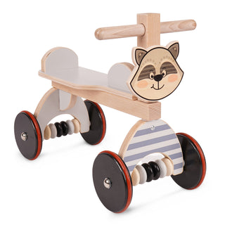 Ein hölzernes Kinderlaufrad mit vier schwarzen Rädern, die rote Ränder und silberne Schrauben in der Mitte haben. Der Sitz und die Rückenlehne bestehen aus hellem Holz. Auf der Vorderseite ist ein freundliches Waschbärgesicht abgebildet. Unter dem Sitz befinden sich auf beiden Seiten zwei schwarze Perlen als Dekoration.