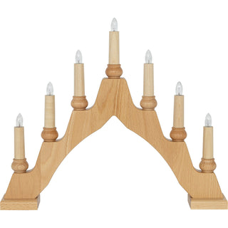 Ein hölzerner Schwibbogen mit sieben elektrischen Kerzen, gleichmäßig verteilt in einem Bogen. Die mittlere Kerze ist am höchsten, die anderen fallen symmetrisch zu den Seiten ab. Jede Kerze hat eine klare Glühbirne. Der Schwibbogen steht stabil auf zwei rechteckigen Füßen.