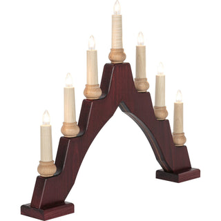 Ein bogenförmiger Schwibbogen mit sieben elektrischen Kerzen. Die mittlere Kerze ist am höchsten, die anderen sind symmetrisch abfallend angeordnet. Der Sockel ist dunkelbraun, die Kerzen sind hell und mit kleinen, leuchtenden Glühbirnen versehen.