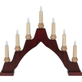 Ein bogenförmiger Schwibbogen aus dunkelrotem Holz mit sieben elektrischen Kerzen. Die Kerzen stehen auf hellen Holzsockeln und sind symmetrisch angeordnet – die mittlere ist am höchsten, die anderen nehmen nach außen hin an Höhe ab. Jede Kerze hat eine klare Glühbirne an der Spitze.