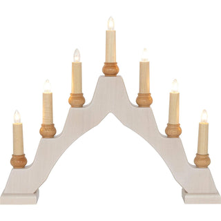 Ein Schwibbogen aus hellem Holz mit sieben elektrischen Kerzen, die auf kleinen Holzhaltern stehen. Die Kerzen sind symmetrisch angeordnet – die mittlere ist am höchsten, die anderen nehmen nach außen hin ab. Jede Kerze hat eine klare, leuchtende Glühbirne.