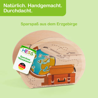 Ovale Spardose aus Holz mit einer bunten Illustration auf der Vorderseite: Ein Globus mit blauen und gelben Kontinenten, ein darüber fliegendes Flugzeug und ein Koffer darunter. Auf der Spardose befindet sich ein Etikett mit der Aufschrift: „HESS Spardose 'Reisekasse' 100% Made in Germany“. Im Hintergrund steht auf grünem Untergrund: „Natürlich. Handgemacht. Durchdacht.“ und „Sparspaß aus dem Erzgebirge“.