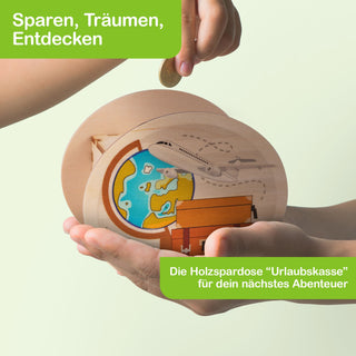 Holzspardose mit Urlaubsdesign, gehalten von einer Hand, während eine andere Hand eine Münze einwirft. Die Dose zeigt eine Illustration mit Globus, Flugzeug und Gepäck. Oben steht der Text „Sparen, Träumen, Entdecken“, unten „Die Holzspardose ‚Urlaubskasse‘ für dein nächstes Abenteuer“.
