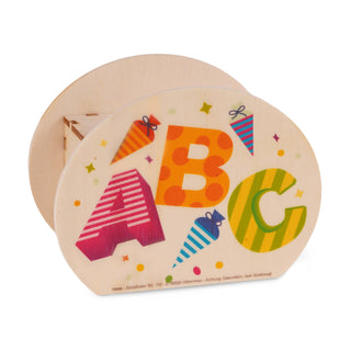 Ovale Spardose aus Holz mit bunten Buchstaben A, B und C auf der Vorderseite. Die Buchstaben sind farbig und gemustert: A ist rot mit weißen Streifen, B orange mit roten Punkten, C grün mit gelben Streifen. Um die Buchstaben sind bunte Konfetti-Punkte und kleine Schultüten verteilt. Unten steht: ‚Hess – Grünthaler Str. 112 – D-09526 Olbernhau – Achtung Dekoration, kein Spielzeug‘.