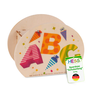 Ovale Spardose aus Holz mit den Buchstaben A, B und C in bunten Farben und Mustern. Um die Buchstaben sind farbige Schultüten abgebildet. Am unteren Rand steht: ‚Hess – Grünthaler Str. 112 – D-09526 Olbernhau – Achtung Dekoration‘. Rechts unten befindet sich ein Etikett mit der Aufschrift: ‚HESS Spardose ‚Schulanfang‘ farbig 100% MADE IN GERMANY‘.