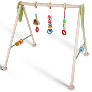 Hölzernes Babyspielgerät in A-Rahmen-Form mit vier Beinen und einer oberen Querstange. Daran hängen drei Spielzeuge: ein Bienenstock mit Biene, ein Fuchs und ein Igel – jeweils mit bunten Perlen und Ringen verziert. An den Seiten befinden sich drehbare, bunte Ringe auf horizontalen Stangen.