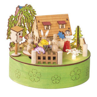 Auf der grünfarbenen Spieluhr befinden sich kleine LED Blüten, die mit 2 x AA Batterien betrieben werden. Dazu befinden sich noch ein Haus, Bäumchen, ein Vogelhaus, ein Blumenkind und ein Karusell mit 3 kleinen Osterhäschen auf der Spieluhr. Alles ist in frühlingshaften Farben gestaltet.  
