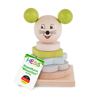 Ein Stapelturm aus Holz in Form einer Maus. Der Turm besteht aus mehreren bunten, stapelbaren Holzscheiben und hat einen Kopf mit aufgemaltem Gesicht sowie zwei grünen Ohren. Ein Etikett am Spielzeug trägt die Aufschrift: „HESS Stapelturm ‚Mäuschen‘ farbig 100% MADE IN GERMANY“.