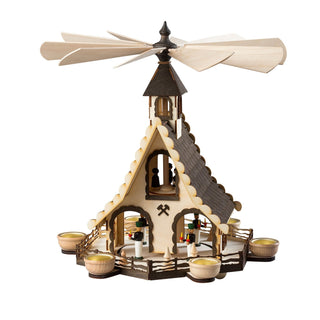 Die Weihnachtspyramide ‚Bergmänner‘ ist 47 cm hoch und für sechs Teelichte ausgelegt. Sie besteht aus einem hölzernen, mehrstöckigen Aufbau mit einem großen Flügelrad an der Spitze, das durch die Wärme der Teelichte angetrieben wird. Die dargestellte Szene zeigt mehrere Bergmänner und weitere Figuren, die um eine zentrale Säule gruppiert sind. Die sechseckige Basis verfügt über sechs symmetrisch angeordnete Teelichthalter.