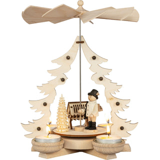 Holz-Weihnachtspyramide mit einem Waldarbeitermotiv, bestehend aus einer Figur eines Waldarbeiters, einem Baum und einer Holzhütte. Die Pyramide hat vier Teelichthalter und ein drehbares Flügelrad oben.