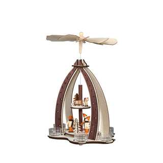 Ein Weihnachtspyramiden-Dekorationsstück aus Holz mit einem drehbaren Flügelrad oben, das durch die Wärme von Teelichten angetrieben wird. Die Pyramide zeigt Winterkinder, Reh, Schlitten und Bäumen auf zwei Ebenen, umgeben von sternverzierten Bögen. Ansicht von rechts.