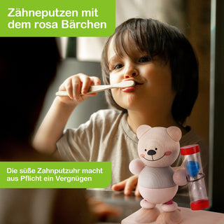 Ein Kind putzt sich die Zähne mit einer Zahnbürste. Im Vordergrund steht eine rosa Zahnputzuhr in Form eines Bärchens. Text im Bild: „Zähneputzen mit dem rosa Bärchen“ und „Die süße Zahnputzuhr macht aus Pflicht ein Vergnügen“.