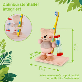Ein Zahnbürstenhalter aus Holz in Form eines Bären. Der Bär hält eine gelbe Zahnbürste mit blauen Borsten und einem blauen Stern auf dem Griff. An seiner Seite ist eine Sanduhr in Blau und Rot befestigt. Der Halter steht auf einer rechteckigen Holzplatte. Text im Bild: „Zahnbürstenhalter integriert“ und „Alles an einem Ort – praktisch & ordentlich im Badezimmer“.