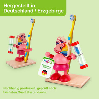 Eine Zahnputzuhr in Form eines Einhorns mit der Aufschrift „HESS Zahnputzuhr ‚Einhorn‘ Made in Germany“. Begleitender Text im Bild: „Hergestellt in Deutschland / Erzgebirge“ und „Nachhaltig produziert, geprüft nach höchsten Qualitätsstandards“.