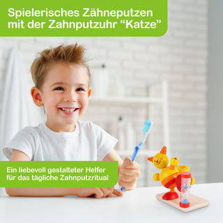 Ein Kind sitzt an einem Tisch und hält eine Zahnbürste in der Hand. Auf dem Tisch steht eine bunte Zahnputzuhr in Form einer Katze mit einer Sanduhr. Im Hintergrund ist ein Badezimmer mit weißen Fliesen und einem Regal zu sehen. Auf dem Bild steht: „Spielerisches Zähneputzen mit der Zahnputzuhr ‚Katze‘“ und „Ein liebevoll gestalteter Helfer für das tägliche Zahnputzritual“.