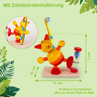 Ein bunter Zahnbürstenhalter in Form einer fröhlichen, gelben Katze mit roten und blauen Akzenten. Die Katze steht auf einem Holzsockel, hält eine Zahnbürste in der rechten Hand und neben ihr befindet sich eine Sanduhr mit rotem Deckel und Boden. Der Halter ist 10 cm hoch und 11 cm breit, die Sanduhr ist 7 cm hoch. Im Bild steht oben „Mit Zahnbürstenhalterung“ und unten rechts „Praktisch & ordentlich – alles an einem Platz im Bad“.