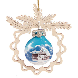 Christbaumschmuck "Winterlandschaft" zeigt eine blaue Kugel mit einem handgemalten Motiv einer verschneiten Hütte. Die Kugel ist in einen filigranen Holzrahmen in Form von Tannenzweigen eingefasst.