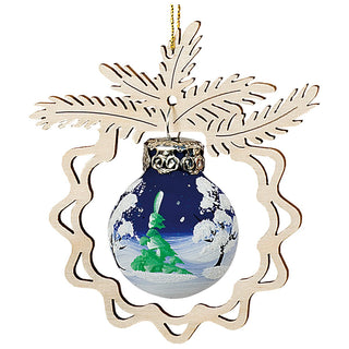 Christbaumschmuck mit winterlicher Waldszene: Eine runde Kugel zeigt eine gemalte Darstellung von schneebedeckten Bäumen vor einem dunkelblauen Nachthimmel. Umrahmt wird die Kugel von einem filigranen Holzschnitt in Form von Tannenzweigen, der das winterliche Motiv stimmungsvoll ergänzt.